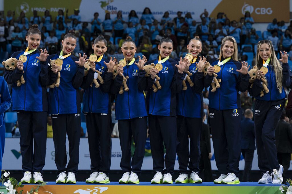 A seleção de conjunto, a treinadora Camila Ferezin e a auxiliar técnica Bruna Martins recebem a medalha de ouro da competição geral. | Foto: MeloGym/CBG